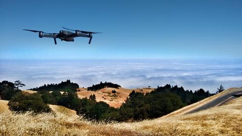 A drone hovers over grassy hills